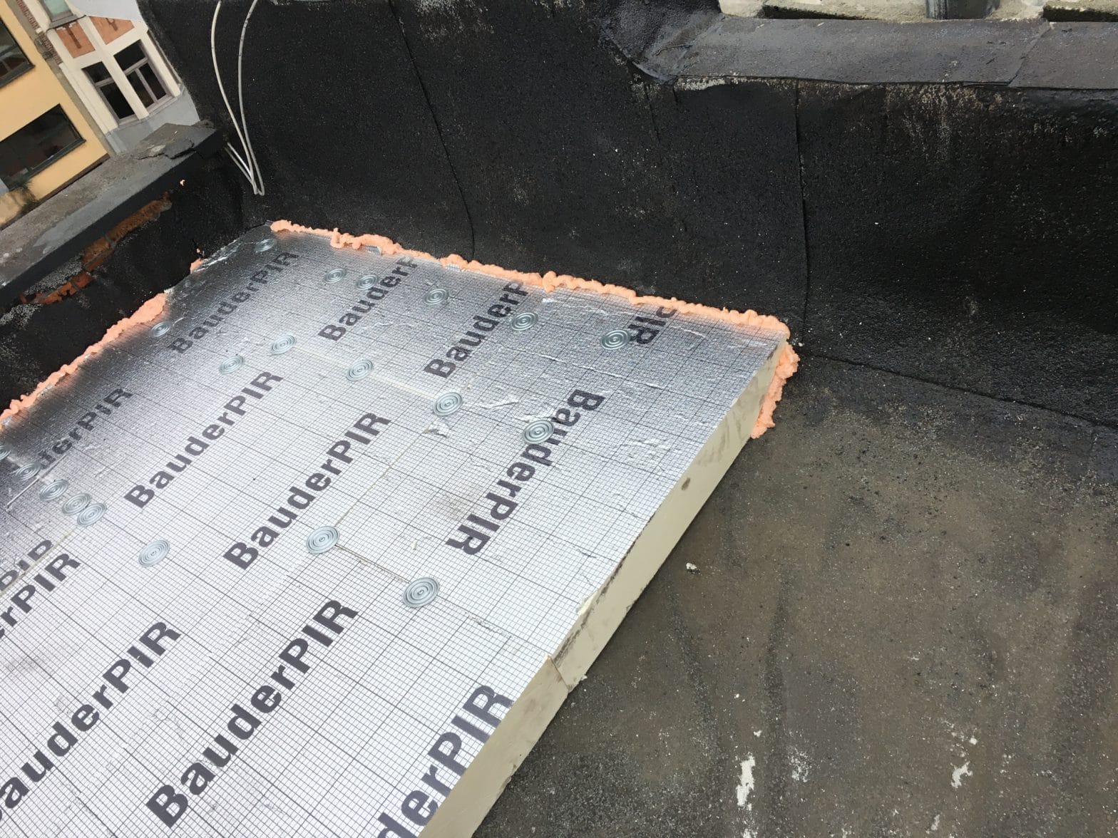 Plat dak in opbouw met BauderPIR-isolatieplaten op een bitumineuze onderlaag, uitgevoerd door T-ROOF